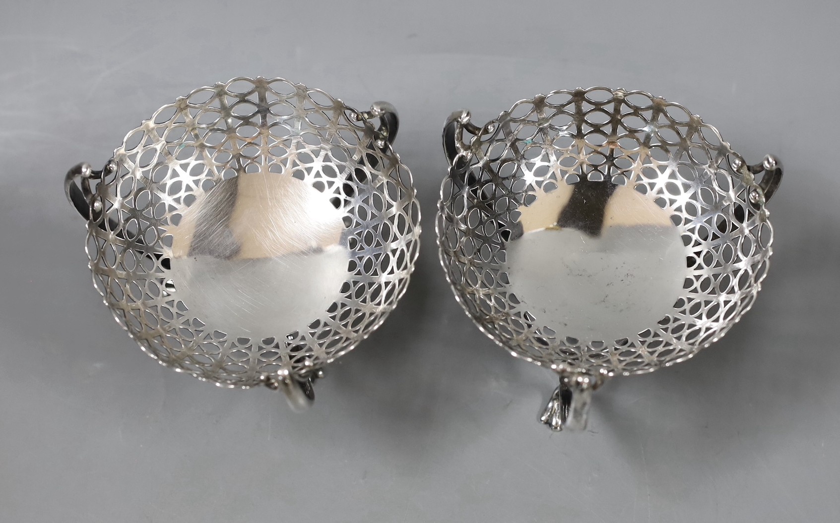 A pair of Edwardian pierced silver bon bon dishes, on raised tripod supports, E.S. Barnsley & Co, Birmingham, 1906, height 81mm, 5.8oz.